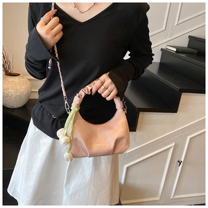 Detail of light pink dumpling bag with pleated handle and golden chain strap