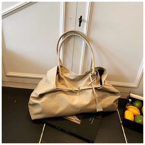 Detail of a large beige soft leather tote bag on a photography book in a stylish setup