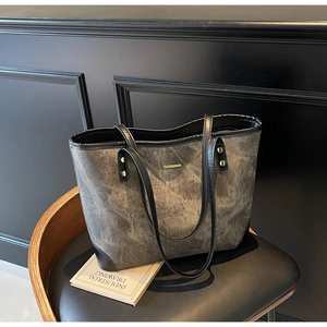 Close-up of vintage grey tote bag with black leather straps and gold metal accents