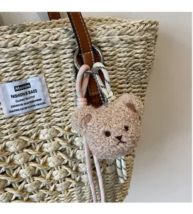 Dettaglio di un ciondolo a forma di orsetto con cordino su una borsa di paglia