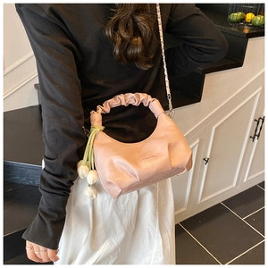 Detail of pink ruched dumpling bag with white flower charms and metal chain strap