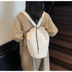 Detail view of cream drawstring bucket bag with black cords on model in stylish setting