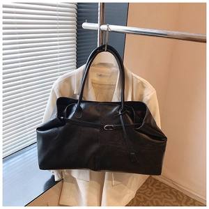 Detail of the black tote bag showing premium matte leather texture and buckle strap design