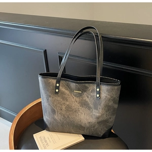 Detail of grey marble textured tote bag with black handles and golden metal hardware