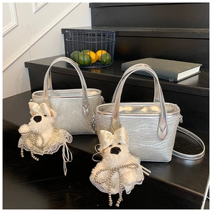 Close-up of silver glitter handbags with wavy texture and cute white plush dog charms
