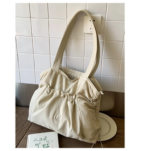 Detail einer großen cremefarbenen Nylon-Tote-Bag mit Kordelzug-Falten auf einem Holztisch
