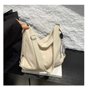 Détails du sac à bandoulière beige montrant le tissu en nylon plissé et la sangle réglable