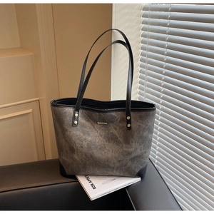 Close-up of marble texture tote bag with black straps and golden rivets on sofa