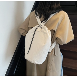 Detail view of white nylon drawstring backpack showing lightweight fabric and stitching