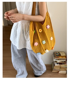 Detail of floral crochet shoulder bag showing 3D knit flowers and yellow hollow mesh weave