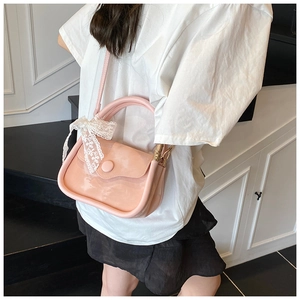 Detail of pink patent leather handbag with a white lace bow and round buckle detail