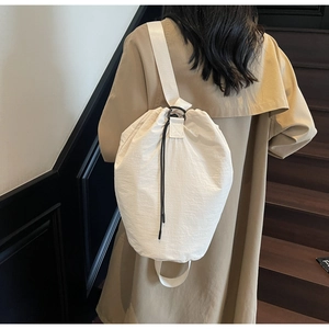 White drawstring bucket bag with adjustable webbing strap shown on a model's back