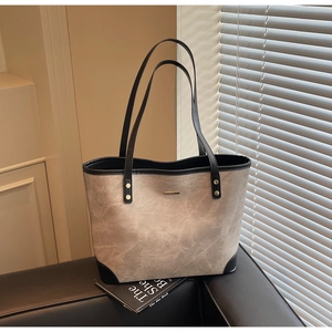 Detail of light khaki tote bag with vintage texture, black straps and gold metal hardware