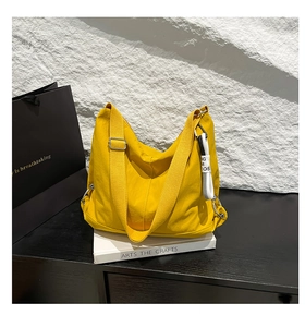 Détail d'un sac hobo en toile jaune vif sur des livres blancs avec un fond noir chic