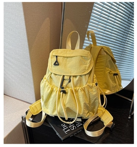 Detail view of yellow nylon backpack with drawstring pockets and mirror reflection showing back
