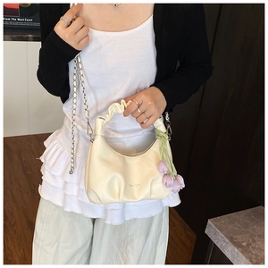 Detail of cream pleated dumpling bag with chain strap and purple tulip floral charm