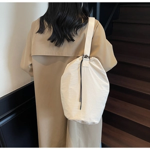 Close-up of cream-colored drawstring bucket bag featuring lightweight nylon fabric texture