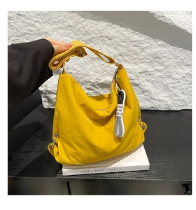 Détail d'un sac dumpling en nylon jaune vif montrant la texture et la bandoulière réglable