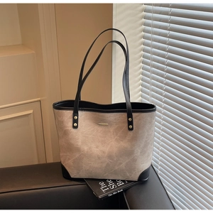 Close-up of beige vintage tote bag with gold rivets and metallic detail on black leather