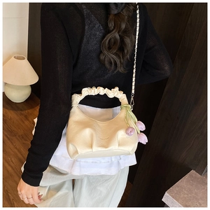 Close-up of beige pleated dumpling bag with tulip charm and gold chain strap detailing