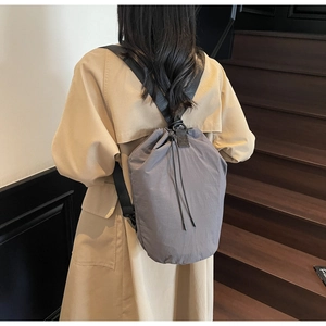 Rear view of model wearing a grey drawstring bucket bag with pleated texture detail
