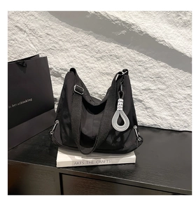 Détail du sac dumpling en nylon noir avec bandoulière large et pendentif anneau argenté