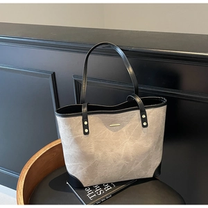 Detail view of large tote bag in grey marble texture with black leather trim and gold hardware