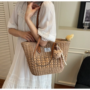 Dettaglio della borsa tote in paglia intrecciata con spalline in pelle marrone