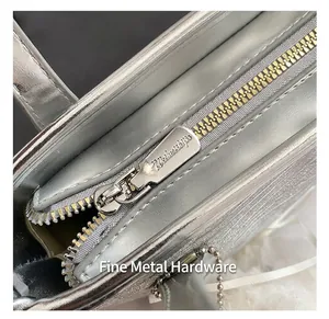 Close-up of golden metal zipper and silver metallic fabric on a crossbody handbag