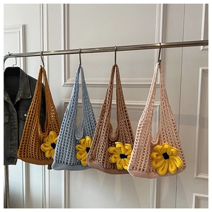Detail of four colorful crochet tote bags with sunflower decorations on a metal rack