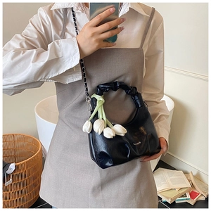 Detail of black glossy dumpling bag with tulip charms and silver chain strap