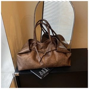 Detail of vintage brown leather tote bag with matte texture and dual long shoulder straps