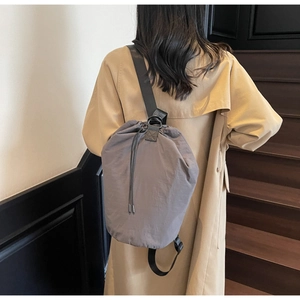 Detail of grey nylon drawstring bucket bag with wide strap on casual trench coat