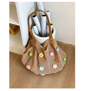 Detail of woven straw bag with colorful crochet flowers and brown leather handle