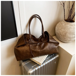 Close-up of retro brown oversized tote bag with vintage leather texture on a suitcase