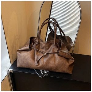 Detailed view of retro brown faux leather tote bag with natural lychee texture on shelf