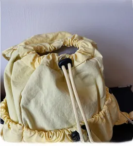Detail of light yellow backpack showing drawstring closure and durable fabric texture