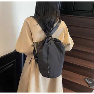 Close-up of black drawstring bucket bag with adjustable strap on a female model