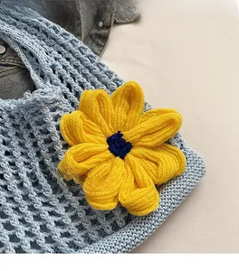 Close-up of crochet mesh tote bag with a yellow sunflower accent and blue knit texture
