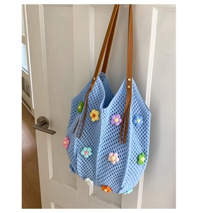 Detail of floral knit tote bag showing colorful 3D crochet flowers and blue weave texture