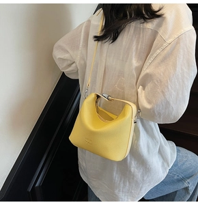 Detail of yellow lychee pattern leather shoulder bag with sleek metal hook fasteners
