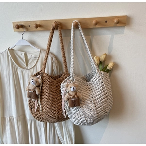 Detail of woven shoulder bags with cute teddy bear pendants in brown and beige