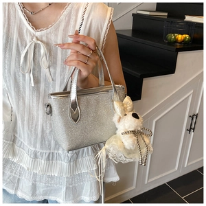 Silver sequin handbag with cute puppy plush charm and double handles in a modern setting