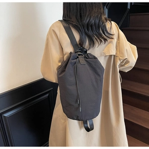 Detail of a casual black drawstring bucket bag showing water-resistant nylon fabric and strap