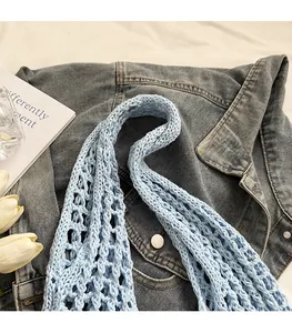 Detail of light blue crochet shoulder strap featuring hollow knit texture and soft cotton yarn