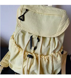Detail of light yellow nylon backpack with drawstring closure and plastic hook