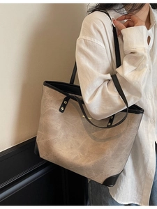 Minimalist beige leather tote bag with black trim and handles for daily commuting