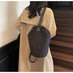 Detail of black nylon drawstring bucket bag showing its textured surface and wide strap