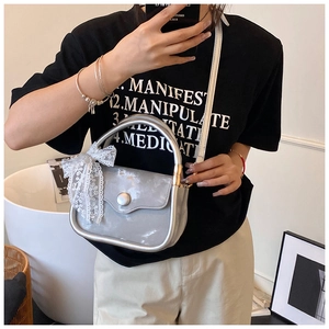 Detail of silver crossbody bag featuring marble texture and a white lace bow accent
