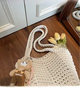 Close-up of off-white hand-woven tote bag with cute brown plush bear charm accessory